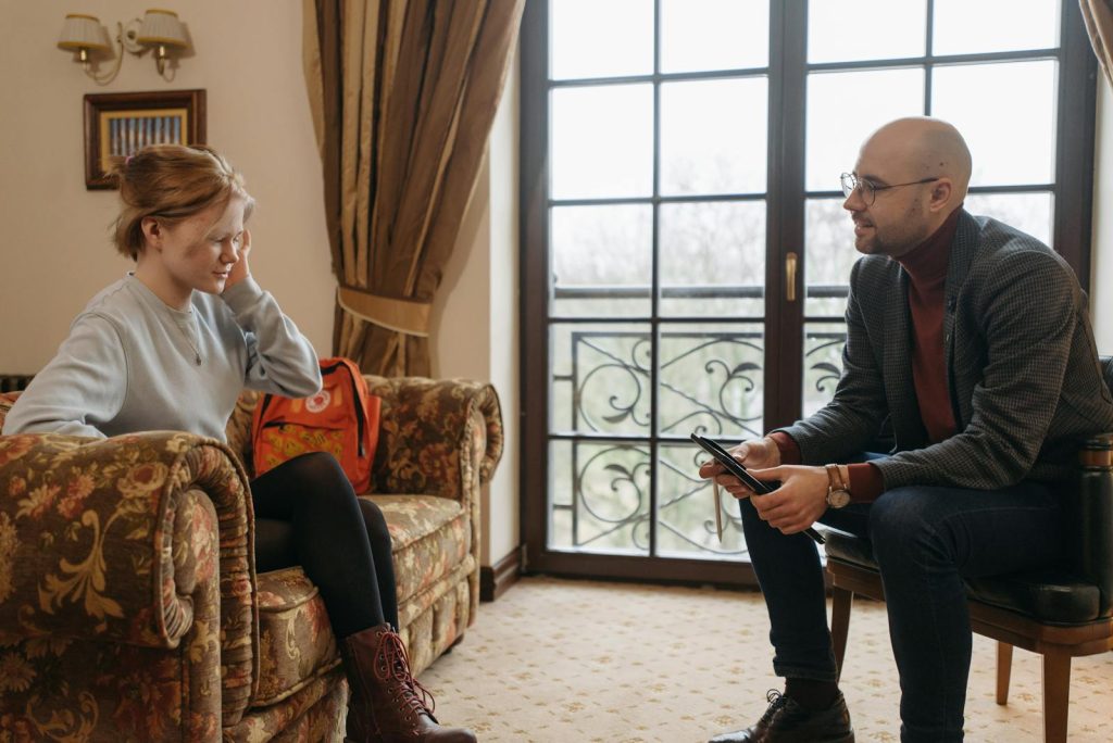 A counselor and client engage in conversation during a therapy session in a cozy room.