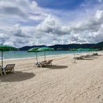 a sandy beach with lawn chairs and umbrellas